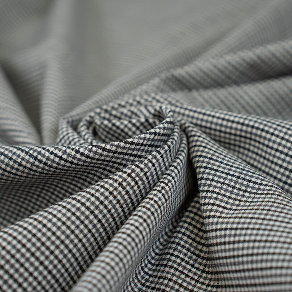 Gray checkered wool and polyester. The fabric is elastic and falling. High-quality deadstock fabric collected in Stock from a Maison de Couture in Italy.
