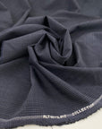 Light wool mixed with polyester with a small checker pattern in dark blue. High-quality deadstock fabric collected in Stock from a Maison de Couture in Italy.