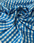 Pure cotton poplin with a small check design, approximately one centimeter squares, in light blue color reference Bu Blue. Very soft, light, flowy, and not transparent. Ideal for shirting, dresses, and skirts. High-quality deadstock collected in Stock from a Maison de Couture in Italy.