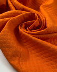 Pure cotton jacquard in vibrant orange, color reference Shakar. Very soft, flowy, and not transparent. Ideal for jackets, dresses, trousers, and skirts. High-quality deadstock collected in Stock from a Maison de Couture in Italy.