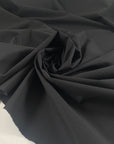 Black microfiber in polyester stretch, color reference tap shoe. A little bit crunchy and light, ideal for jackets, trenches, and trousers. High-quality deadstock collected in Stock from a Maison de Couture in Italy.