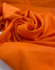 Silk with polyester and viscose in a very bright orange. The fabric is structured. High-quality deadstock fabric collected in Stock from a Maison de Couture in Italy.