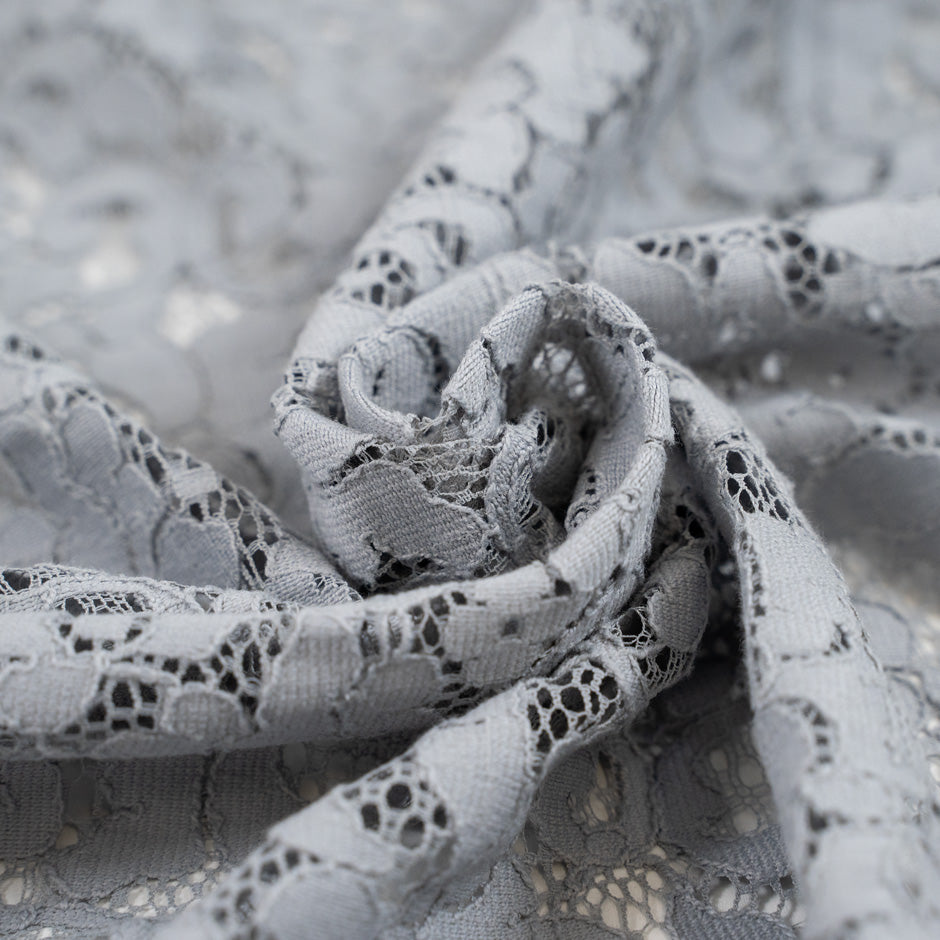 Gray cotton and polyester rebrodè lace fabric. It is falling and transparent. High-quality deadstock fabric collected in Stock from a Maison de Couture in Italy.