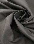 Pure cotton fabric in smoked pearl gray, with a crunchy hand and stiff structure, ideal for sculptural pieces, shirts, and outerwear. High-quality deadstock collected in Stock from a Maison de Couture in Italy.