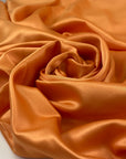 Matte orange polyester satin with a smooth hand and elegant drape perfect for fluid dresses and bold details. High-quality deadstock collected in Stock from a Maison de Couture in Italy.