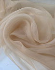 Light and transparent polyester organza in a shiny beige tone. Ideal for dresses, skirts, blouses, and shirting. High-quality deadstock collected in Stock from a Maison de Couture in Italy.