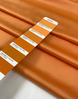 Matte orange polyester satin with a smooth hand and elegant drape perfect for fluid dresses and bold details. High-quality deadstock collected in Stock from a Maison de Couture in Italy.