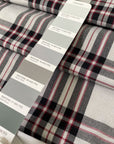 Soft and flowy polyester and viscose fabric with a check design in shades of gray and black, accented by subtle red stripes. Ideal for jackets, trousers, skirts, and dresses. High-quality deadstock collected in Stock from a Maison de Couture in Italy.