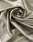 Polyester satin in sage green color reference elm. Very soft, light, and flowy with a matte finish. Not transparent. Ideal for dresses, skirts, and shirting. High-quality deadstock collected in Stock from a Maison de Couture in Italy.