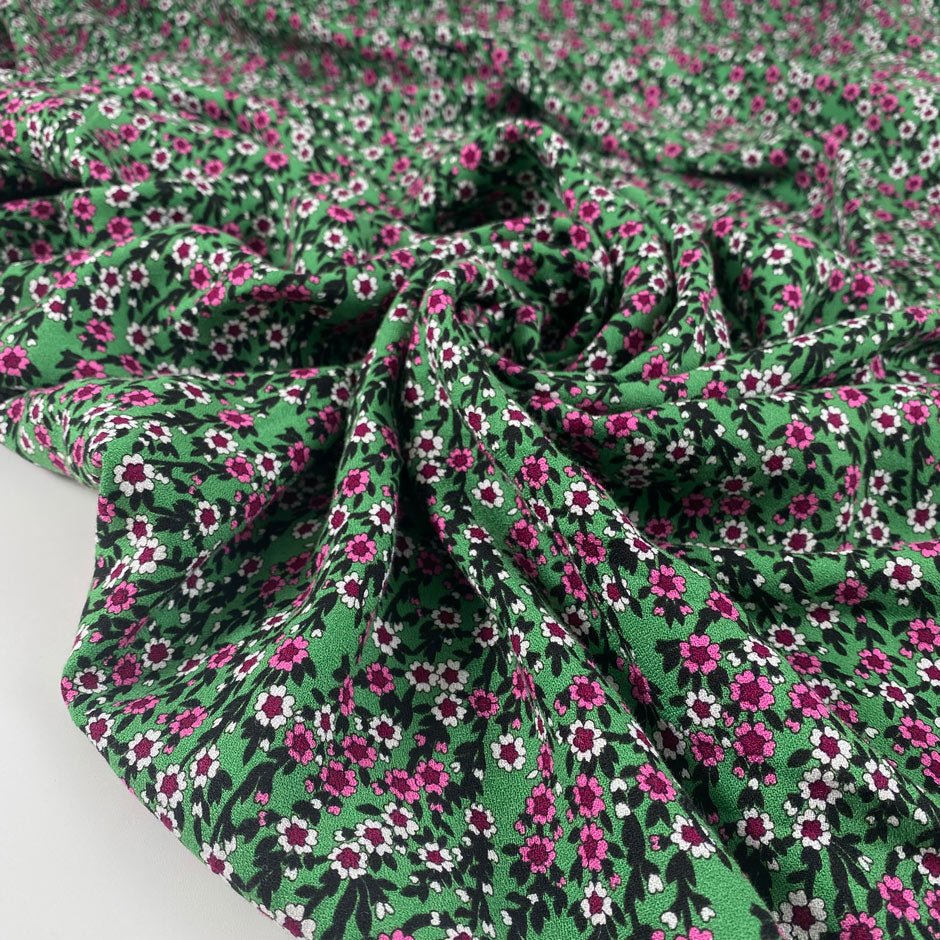 Viscose and wool crepe with a beautiful small flower design, the ground is green and the flowers are in white, fuchsia, and black shades. It is very soft and light. High-quality deadstock fabric by the meter collected in Stock from a Maison de Couture in Italy.