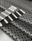 Polyester and elastane satin with small geometric design in shades of grey, white, and black, very soft, light, flowy, not transparent, with a shiny effect. High-quality deadstock collected in Stock from a Maison de Couture in Italy.