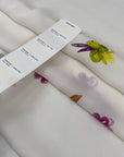 Pure silk crepe de chine in white background, very soft and light with beautiful flower printed in yellow, orange, purple and green shades. A little transparent. High-quality deadstock fabric by the meter collected in Stock from a Maison de Couture in Italy. | Pantone 11-0607 TPG