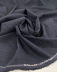 Light wool mixed with polyester with a small checker pattern in dark blue. High-quality deadstock fabric collected in Stock from a Maison de Couture in Italy.