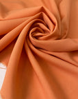 Light wool stretch in orange color reference Copper Tan. Very soft and light, flowy and not transparent. Ideal for dresses, trousers, skirts, and blouses. High-quality deadstock collected in Stock from a Maison de Couture in Italy.