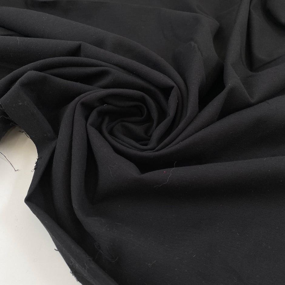 Very soft and warm-touch stretch cotton in black. Lightweight and solid color. High-quality deadstock collected in Stock from a Maison de Couture in Italy.