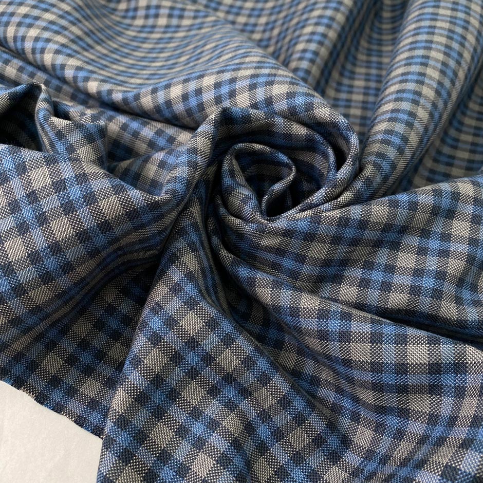 Mixed wool, silk, and cotton with a small check design in the shades of light blue and gray, color reference Blue Jasper. Very soft, medium weight, and flowy. Ideal for trousers, skirts, and jackets. High-quality deadstock collected in Stock from a Maison de Couture in Italy.