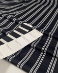 Black base Punto Milano polyester with double white lines. The fabric is stretch. High-quality deadstock collected in Stock from a Maison de Couture in Italy.