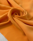 Medium-weight polyester cady in Iceland orange. Puffy, very soft and flowy, not transparent. Ideal for trousers, skirts, dresses, and heavy blouses. High-quality deadstock collected in Stock from a Maison de Couture in Italy.