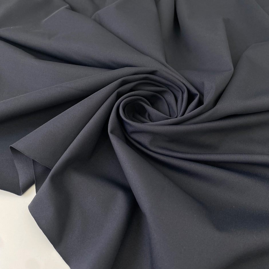Stretch Lycra in dark gray color reference Ebony. Very soft, flowy, and ideal for swimsuits, shapewear, dresses, and skirts. High-quality deadstock collected in Stock from a Maison de Couture in Italy.