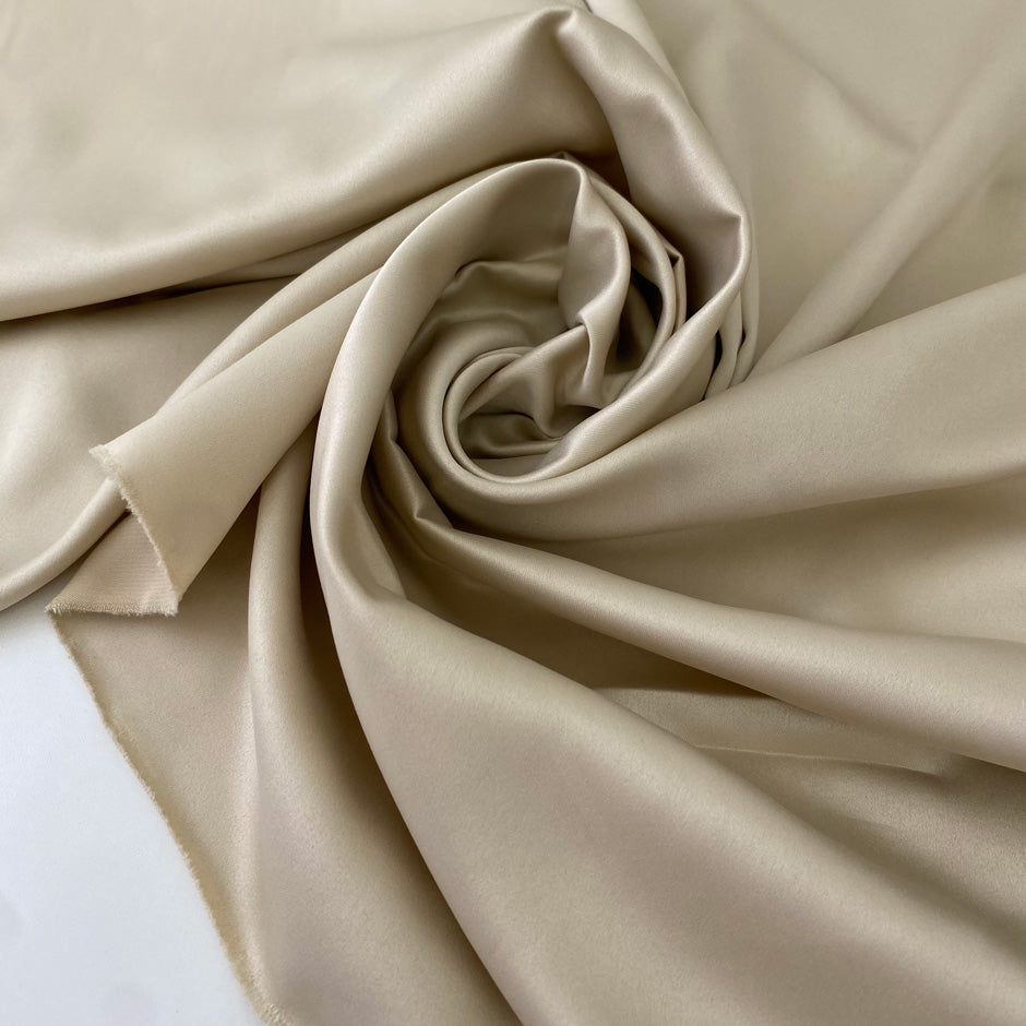 Polyester satin in cream color. Very soft, light, and flowy. Not transparent. Ideal for dresses, skirts, blouses, and shirting. High-quality deadstock collected in Stock from a Maison de Couture in Italy.