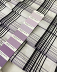 Checked fabric in a wool and cotton blend with a taffeta-like texture that keeps its shape and adds volume. In shades of white, black, and lilac. Ideal for dresses, skirts, and shirting. High-quality deadstock collected in Stock from a Maison de Couture in Italy.