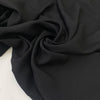 Black polyester crêpe with a fluid drape and slightly textured matte surface ideal for dresses trousers and soft tailoring. High-quality deadstock collected in Stock from a Maison de Couture in Italy.