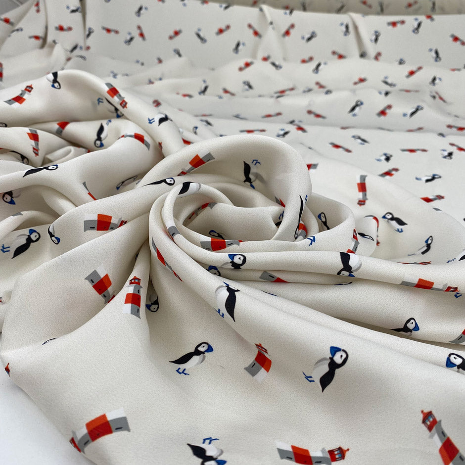 Very soft and light polyester satin with ivory ground and small fantasy design of birds and lighthouses. Not transparent. High-quality deadstock collected in Stock from a Maison de Couture in Italy.