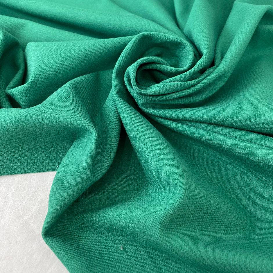 Viscose and elastane stretch Punto Milano jersey in green color reference Rolling Hills. Very soft and flowy, slightly heavy, ideal for trousers, skirts, jackets, and dresses. High-quality deadstock collected in Stock from a Maison de Couture in Italy.