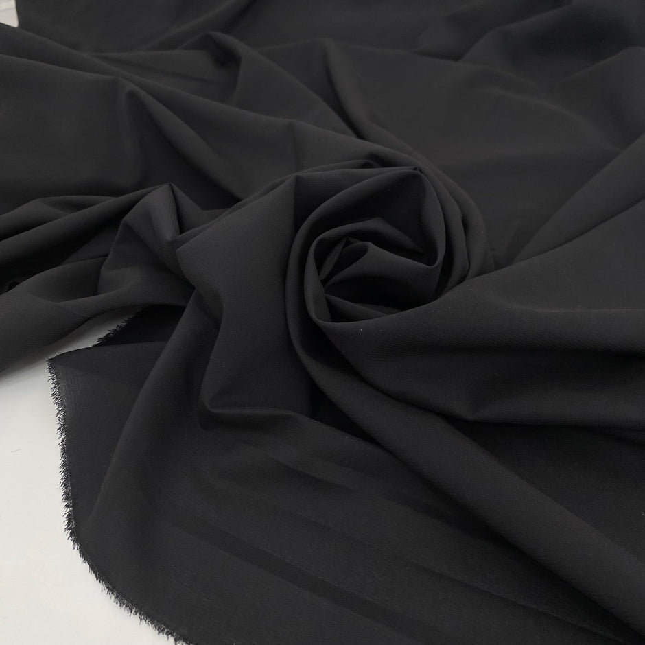 Very soft and flowing polyester georgette in a dark gray shade, color reference Meteorite. Ideal for dresses, skirts, blouses, and shirting. High-quality deadstock collected in Stock from a Maison de Couture in Italy.