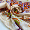Printed polyester twill in panels. The ground is light peach and the print is in shades of bright orange, lilac, and green. Very flowy, a little shiny. &nbsp;High-quality deadstock collected in Stock from a Maison de Couture in Italy.