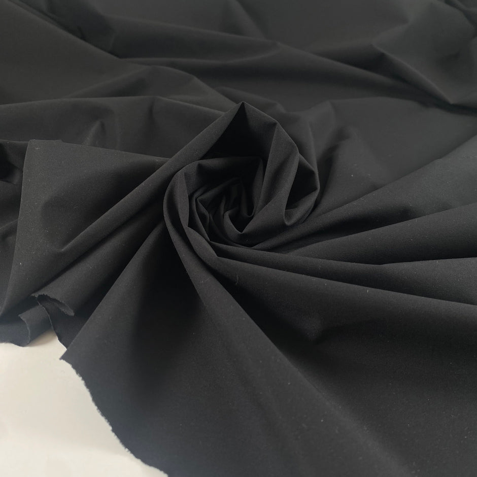 Black microfiber in polyester stretch, color reference tap shoe. A little bit crunchy and light, ideal for jackets, trenches, and trousers. High-quality deadstock collected in Stock from a Maison de Couture in Italy.