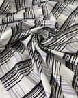 Checked fabric in a wool and cotton blend with a taffeta-like texture that keeps its shape and adds volume. In shades of white, black, and lilac. Ideal for dresses, skirts, and shirting. High-quality deadstock collected in Stock from a Maison de Couture in Italy.