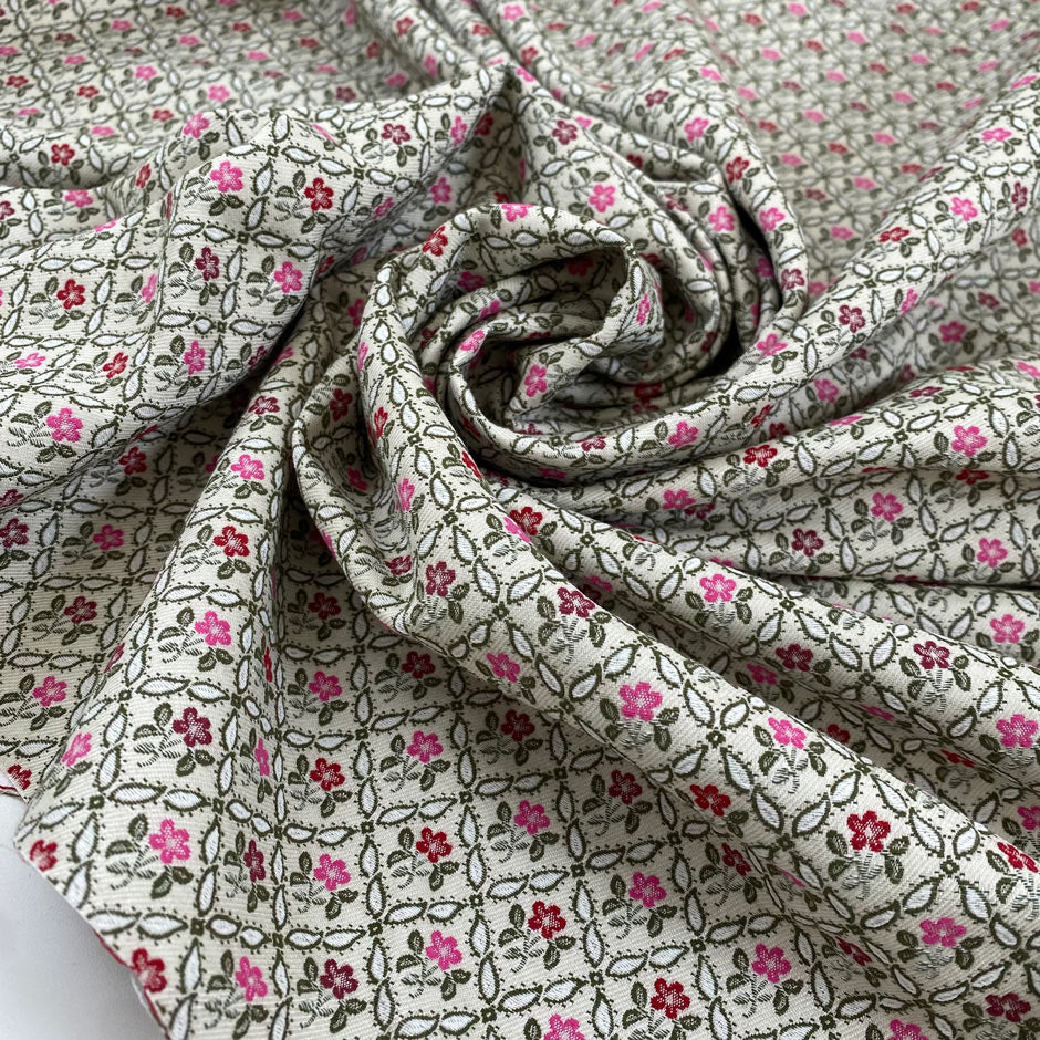Brocade with a very small floral design, the ground is ivory and green with pink carnation and urban red flowers. Soft and structured, ideal for skirts, trousers, and jackets. High-quality deadstock fabric by the meter collected in Stock from a Maison de Couture in Italy.