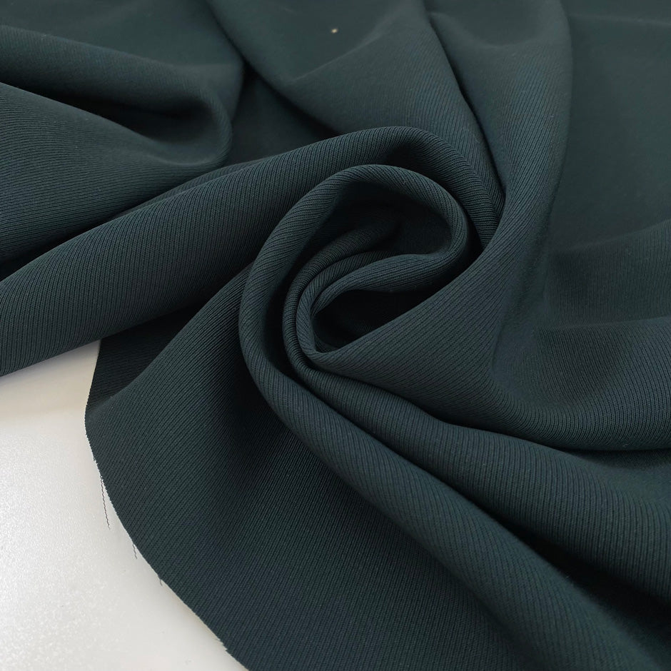 Pure wool in dark forest green with texture. A little bit stiff but flowy and medium weight. Ideal for jackets, skirts, trousers, and light coats. High-quality deadstock collected in Stock from a Maison de Couture in Italy.