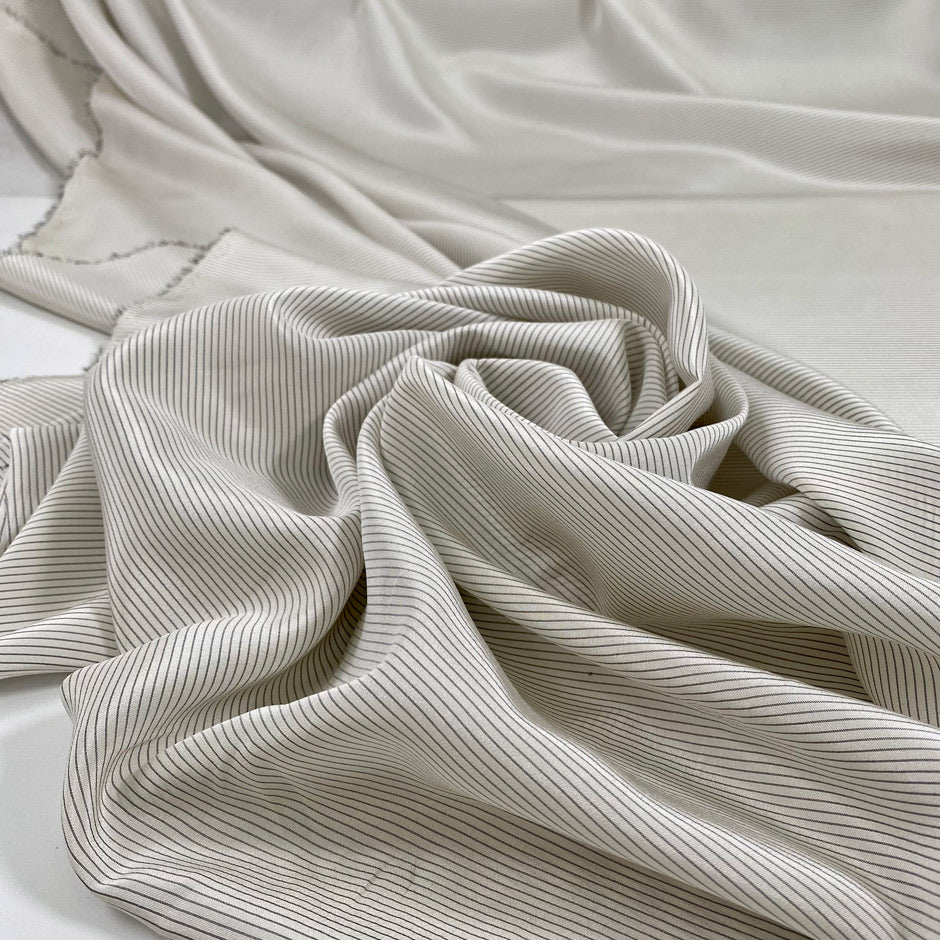 Pure silk crepe de chine with an ivory ground and gray stripes. Very soft and flowy, not transparent. Ideal for dresses, blouses, skirts, and shirting. High-quality deadstock collected in Stock from a Maison de Couture in Italy.