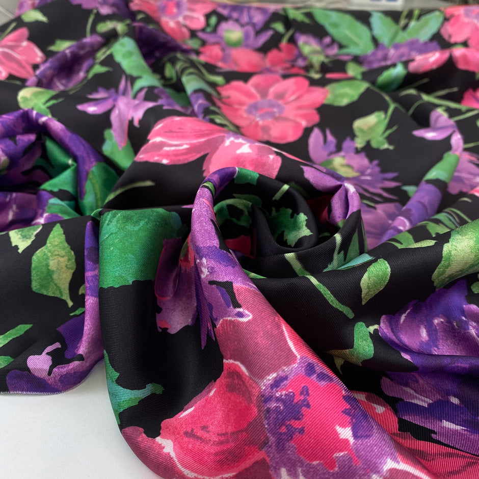 Polyester twill with beautiful flower design. The ground is black and the shades of the flowers are violet, hot pink an,d green. Very soft, light, and flowy. High-quality deadstock fabric by the meter collected in Stock from a Maison de Couture in Italy.