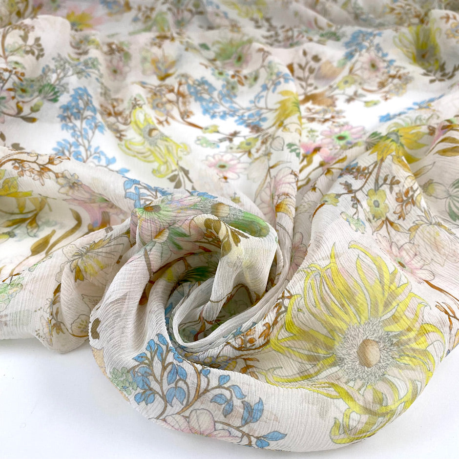 Printed pure silk chiffon with white ground crepon structure. The print is in shades of yellow, light blue, and brown. Very soft and light. High-quality deadstock fabric collected in Stock from a Maison de Couture in Italy.