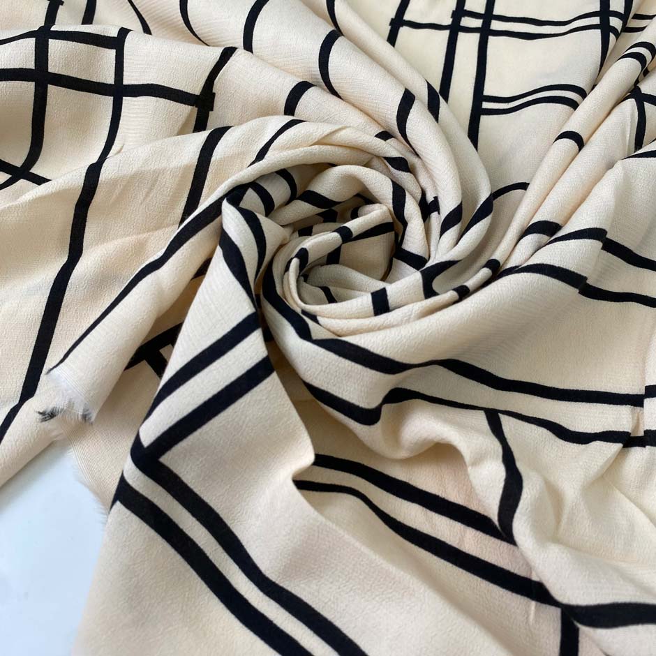 Pure viscose in light peach with a black geometric design. Very soft, flowy, and not transparent. Ideal for dresses, skirts, blouses, and shirting. High-quality deadstock collected in Stock from a Maison de Couture in Italy.