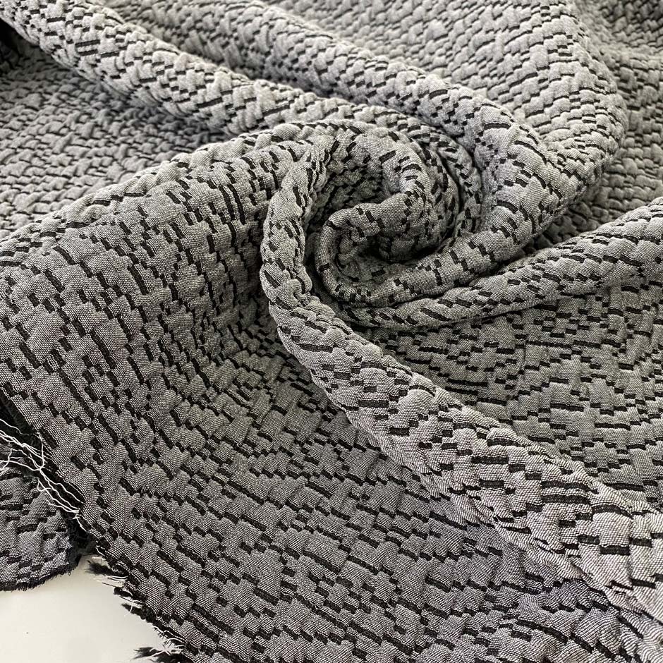 Jacquard fabric in gray with textured surface. A soft and heavy mix of polyester, viscose, and wool, ideal for light coats, jackets, dresses, and skirts. High-quality deadstock collected in Stock from a Maison de Couture in Italy.