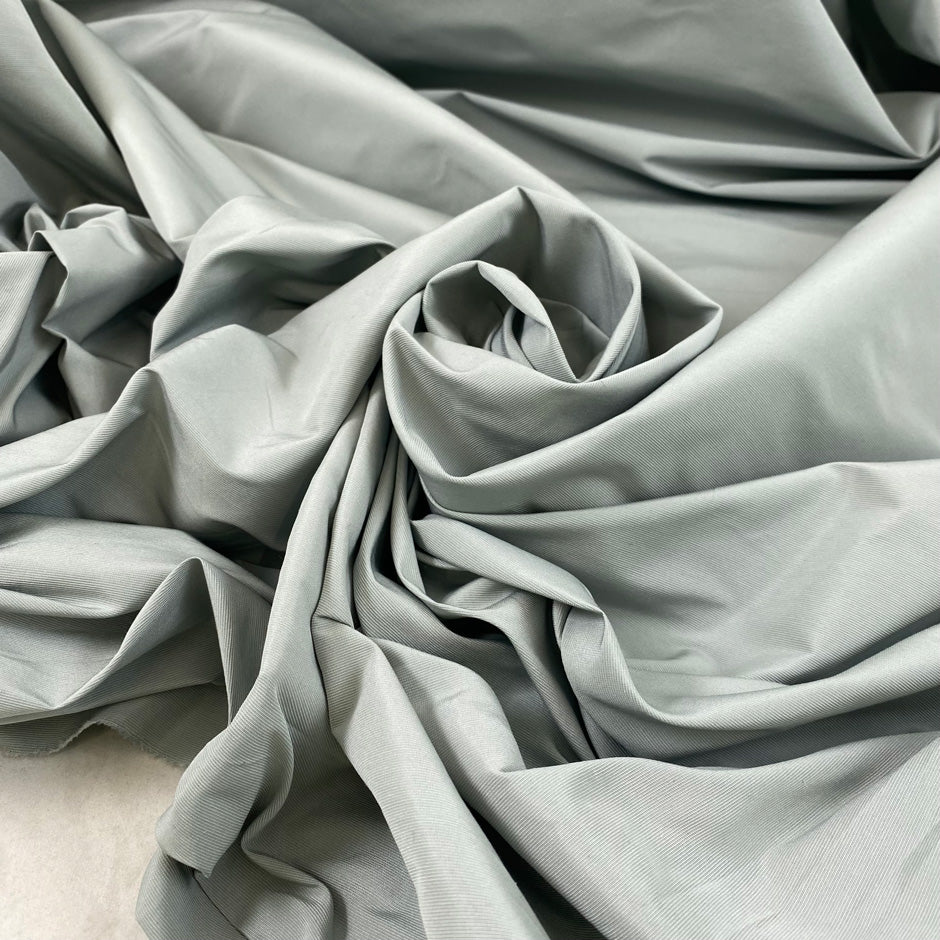 Cotton and polyester taffeta in Mirage Gray with a textured finish. Slightly stiff and shape-retaining, ideal for jackets, skirts, and dresses. High-quality deadstock collected in Stock from a Maison de Couture in Italy.