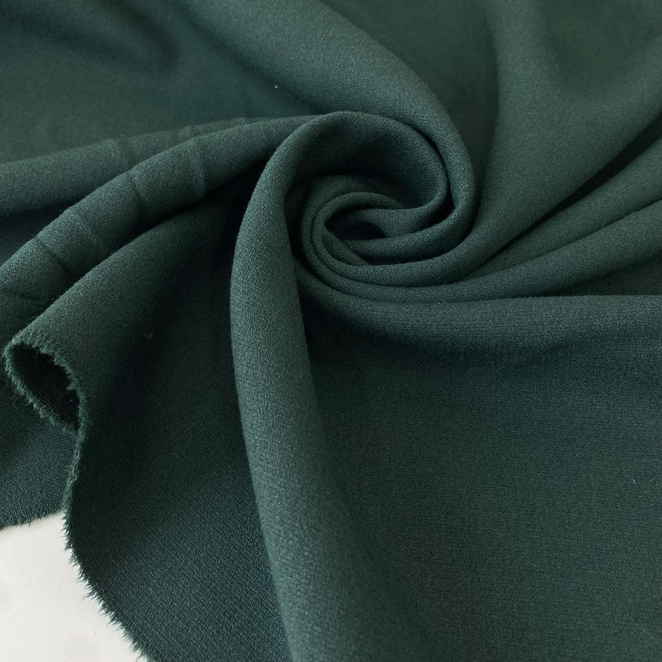 Soft and flowing wool and viscose stretch double crêpe in dark green. Perfect for jackets, skirts, and dresses.High-quality deadstock collected in Stock from a Maison de Couture in Italy.