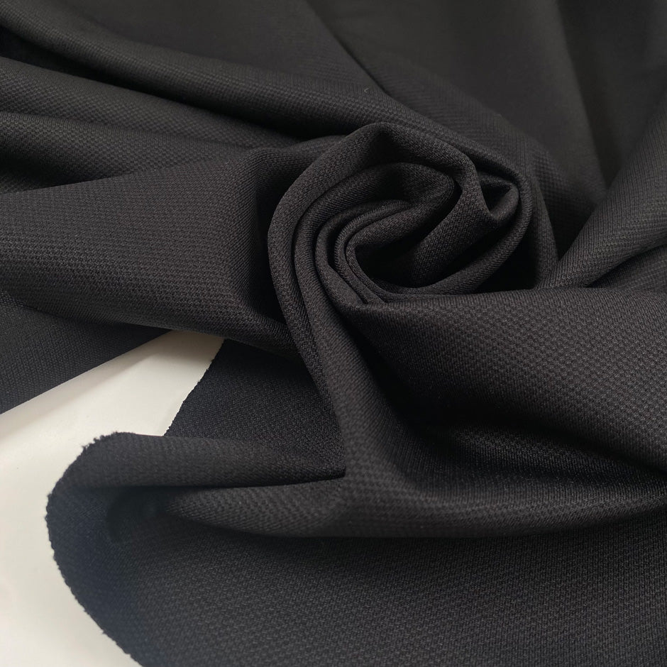Stretch jersey piquet in polyester and elastane, black color reference Tap Shoe. Very soft, flowy, medium weight and not transparent. Ideal for trousers, dresses, skirts, and jackets. High-quality deadstock collected in Stock from a Maison de Couture in Italy.
