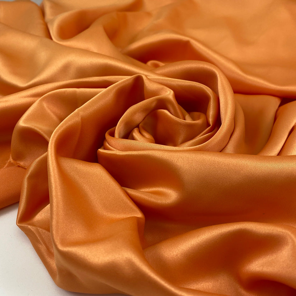 Matte orange polyester satin with a smooth hand and elegant drape perfect for fluid dresses and bold details. High-quality deadstock collected in Stock from a Maison de Couture in Italy.