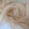 Light and transparent polyester organza in a shiny beige tone. Ideal for dresses, skirts, blouses, and shirting. High-quality deadstock collected in Stock from a Maison de Couture in Italy.
