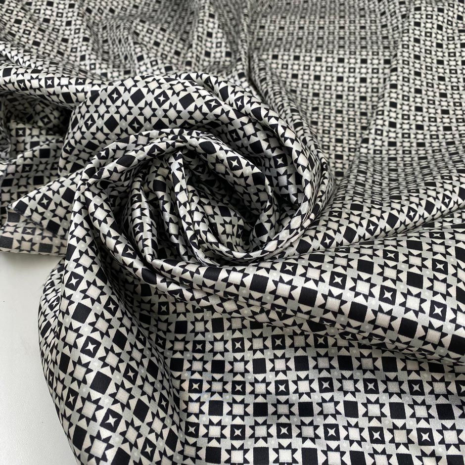 Polyester and elastane satin with small geometric design in shades of grey, white, and black, very soft, light, flowy, not transparent, with a shiny effect. High-quality deadstock collected in Stock from a Maison de Couture in Italy.