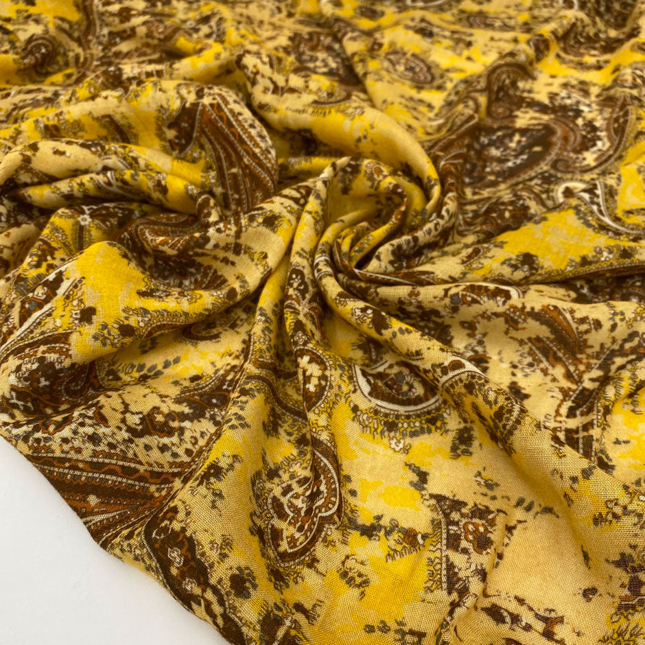 Very soft and light viscose muslin with a paisley design in mustard and brown. Flowy and not transparent, ideal for scarves, light shirting, and airy dresses. High-quality deadstock collected in Stock from a Maison de Couture in Italy.