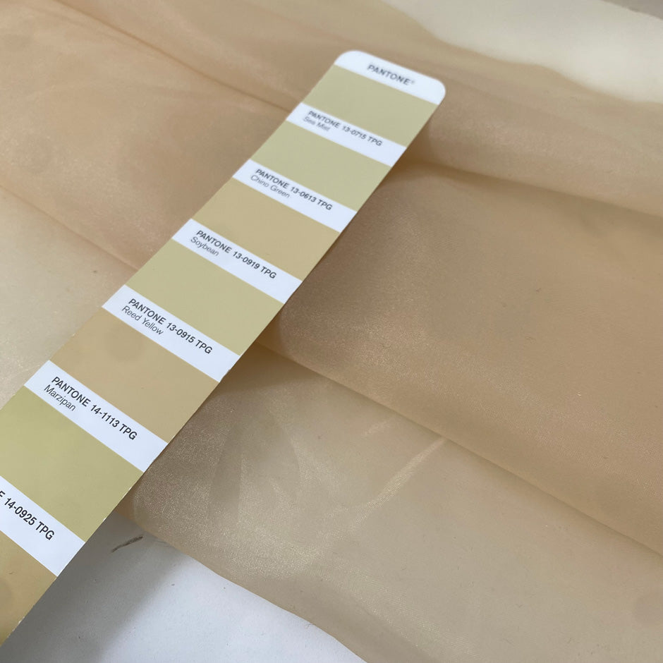 Light and transparent polyester organza in a shiny beige tone. Ideal for dresses, skirts, blouses, and shirting. High-quality deadstock collected in Stock from a Maison de Couture in Italy.