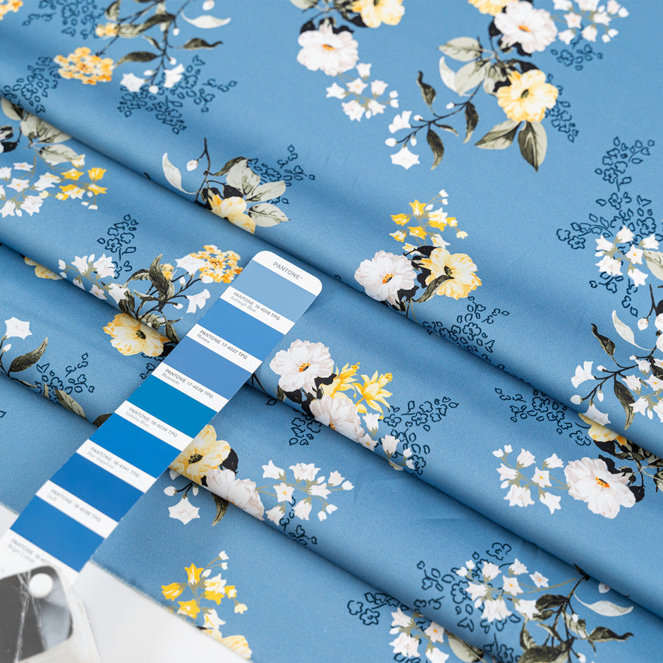 Light blue twill polyester in white and yellow floral design. The fabric is shiny and falling. High-quality deadstock fabric collected in Stock from a Maison de Couture in Italy.