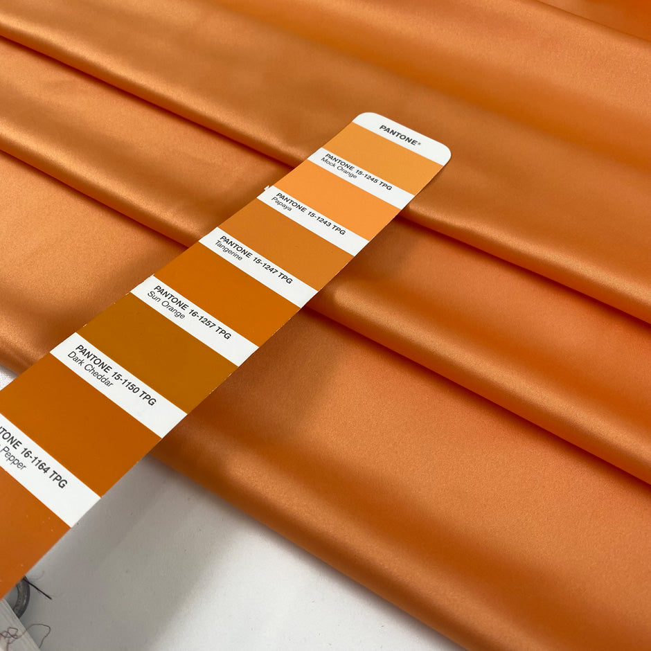 Matte orange polyester satin with a smooth hand and elegant drape perfect for fluid dresses and bold details. High-quality deadstock collected in Stock from a Maison de Couture in Italy.