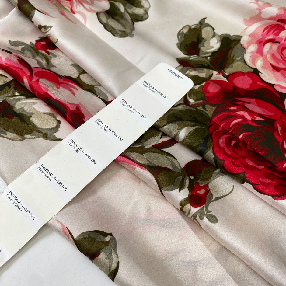 Polyester satin printed with a large floral design in shades of green, red, and fuchsia on an ivory background. Very soft and light, flowy, and ideal for dresses, blouses, shirting, and skirts. High-quality deadstock collected in Stock from a Maison de Couture in Italy.